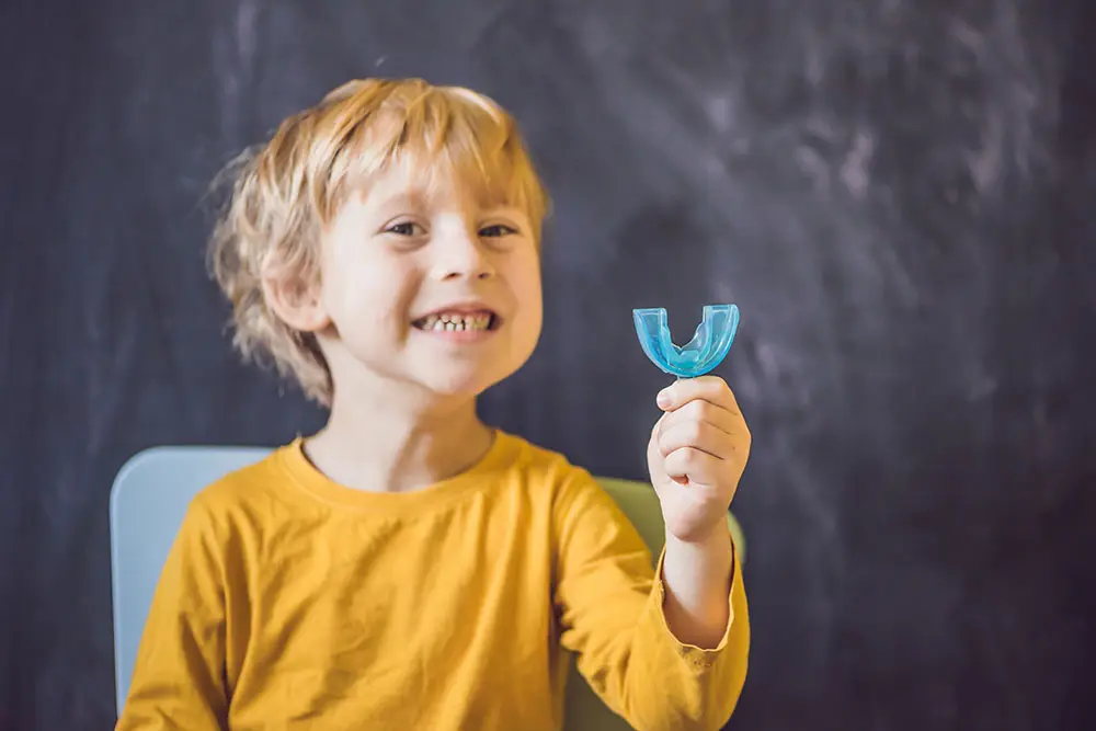 Little boy holding a mouthguard