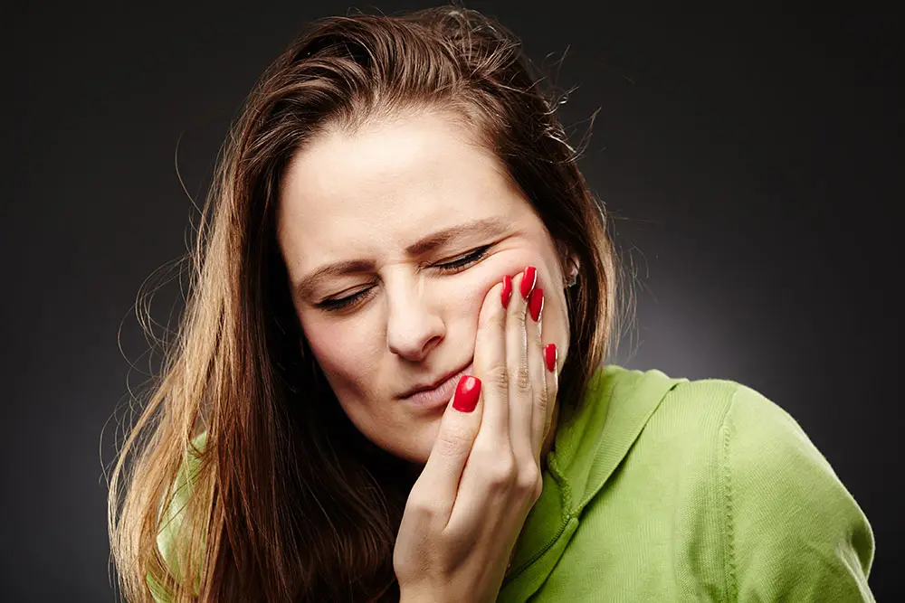 Girl holding her cheek showing she is in pain